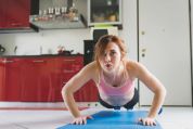 Junge, rothaarige Frau macht in der Küche auf einer Yogmatte Liegestütze Junge, rothaarige Frau macht in der Küche auf einer Yogmatte Liegestütze